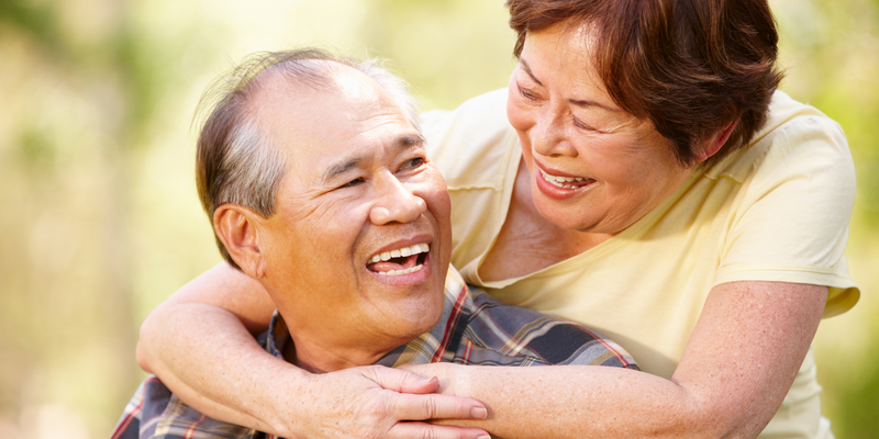 a woman embracing a man from behind and smiling at each other