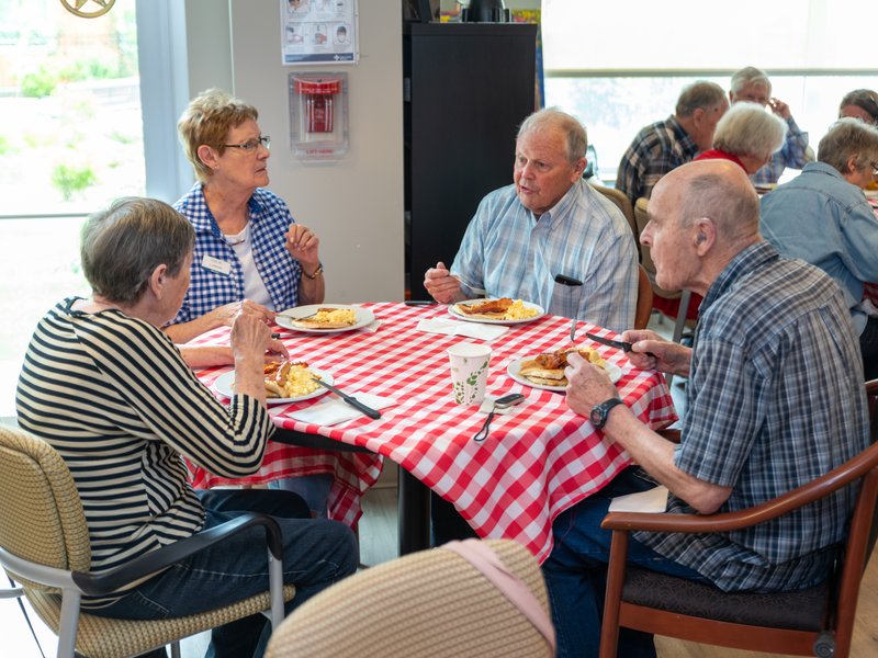a group of people sitting at a breakfast table and talking